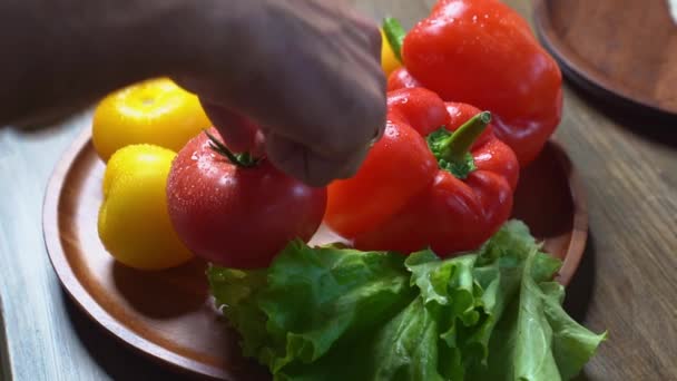 Разбрасывать помидоры, огурцы, салат и сладкий перец на деревянной круглой доске — стоковое видео