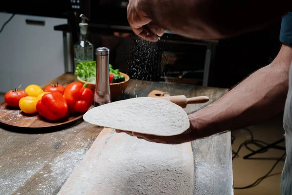 Mãos mens segurar um pão fino. Cozinhar pizza, macarrão ou pitta em casa — Fotografia de Stock