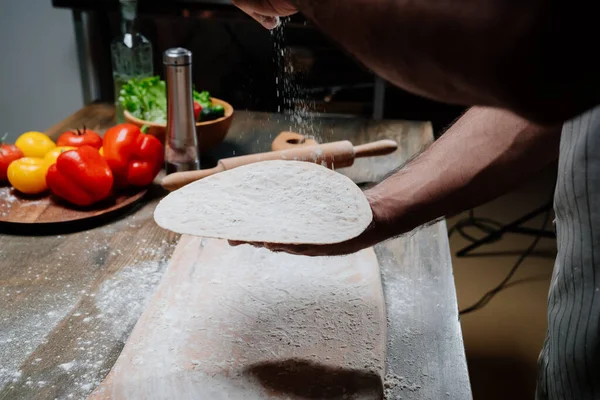 Mãos mens segurar um pão fino. Cozinhar pizza, macarrão ou pitta em casa — Fotografia de Stock