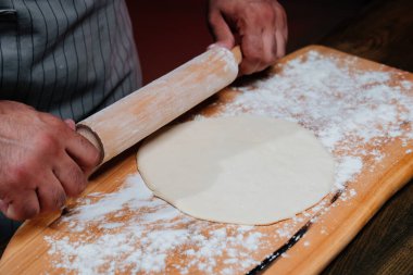 Eller hamuru ince bir tabakaya sarar. Evde pizza, erişte ya da pitta pişiriyorum.