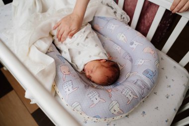 Annelerin elleri yeni doğan bebeğin beşiğinde uyurken battaniyeyi düzeltir.. 