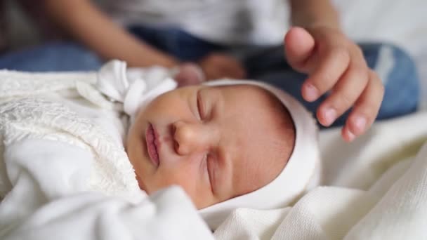 El hermano mayor toca al más joven. lindo bebé recién nacido duerme — Vídeo de stock