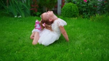 Beyaz elbiseli küçük bir kız çimenlikte akrobatik bir egzersiz yapıyor.. 