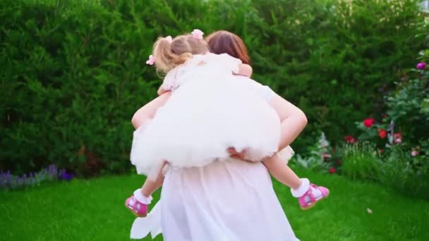 แม่และลูกสาวในชุดสีขาว มีความสนุกสนานและเล่นบนสนามหญ้าในสวนหลังบ้าน — วีดีโอสต็อก