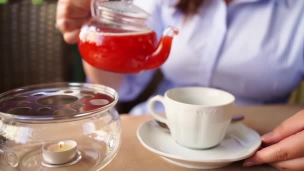 Nahaufnahme. Eine Frau gießt Tee in einen weißen Becher. Heiße Getränke in einem Café — Stockvideo