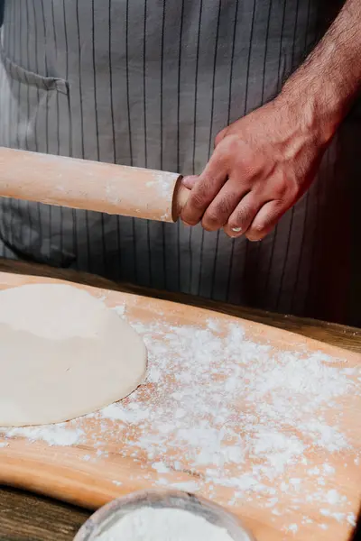 Руки розкачують тісто в тонкий шар. Готуємо піцу, локшину або піту в домашніх умовах — стокове фото