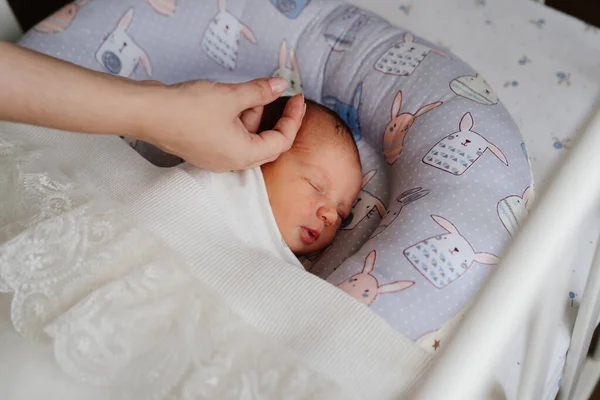 Las manos de las mamás enderezan la manta al dormir en la cuna del recién nacido. — Foto de Stock