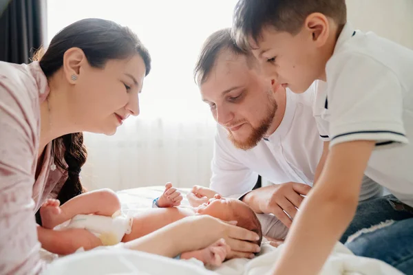 First day of newborn at home. Happy family looking at the newborn in the bedroom — Stock Photo, Image