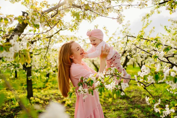 Мать с ребенком на руках в цветущем саду. операция для ребенка с расщелиной губы. — стоковое фото