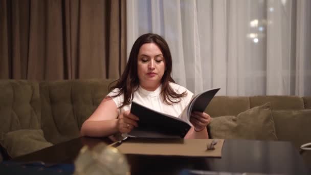 Uma mulher lê o menu e pede pratos no restaurante. Opções alimentares. — Vídeo de Stock