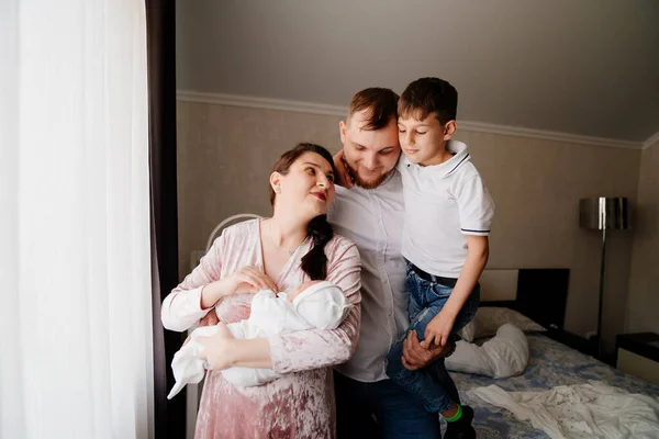 Familia feliz con un niño pequeño en el dormitorio. el primer día del recién nacido en casa — Foto de Stock