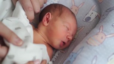 Annelerin elleri yeni doğan bebeğin beşiğinde uyurken battaniyeyi düzeltir.. 