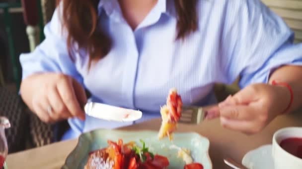 Руки крупним планом. Жінка їсть круасан з полуницею, м'ятою та варенням — стокове відео