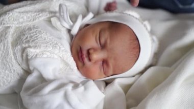 Yeni doğan bebek beyaz giysiler içinde uyur. Hastaneden taburcu olmak için..
