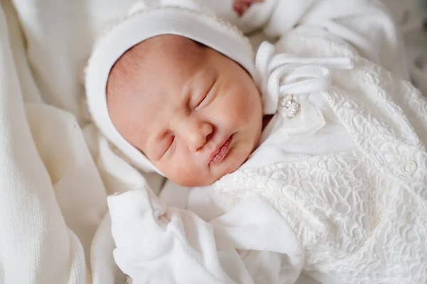 Das süße Neugeborene schläft in weißer Kleidung. Kleidung für die Entlassung aus dem Krankenhaus. — Stockfoto