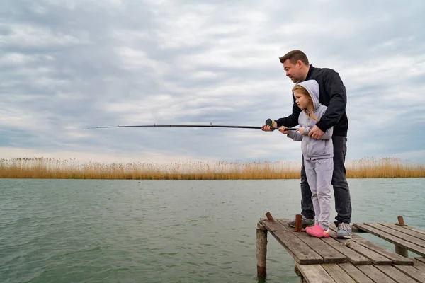 Pai e filha em uma ponte de madeira pegar peixes do rio. — Fotografia de Stock