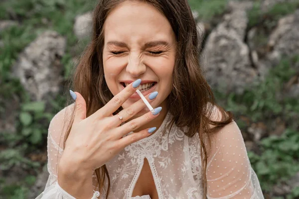 Una joven alegre con un cigarrillo se ríe y fuma. hábito nocivo. — Foto de Stock