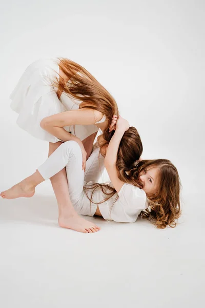 Two cheerful girls with long hair in white clothes play, have fun. — Stock Photo, Image