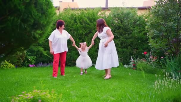 Mutter, Großmutter und Tochter haben Spaß und spielen auf dem Rasen im Hinterhof — Stockvideo
