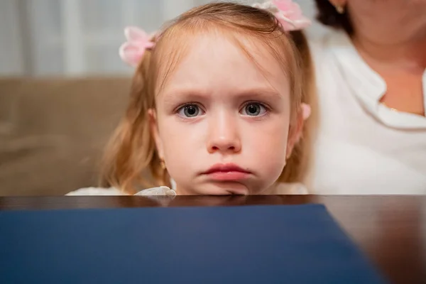 Triste chica se sienta apoyada en la barbilla contra la mesa y la espera de orden en la cafetería. — Foto de Stock