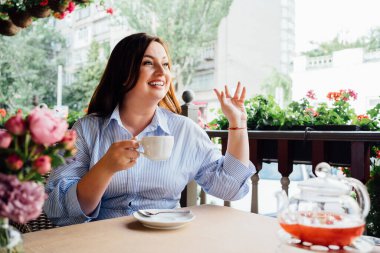 Mavi elbiseli çekici bir kadın kafe çayı içer..