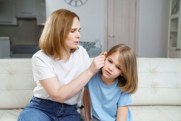a girl complains of pain in ear and her mother examines it. childrens diseases.