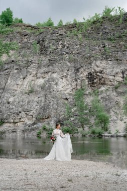 Dağ nehrinin kıyısında beyaz gelinlikli gelin..