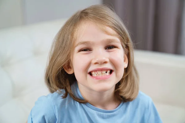 Klein meisje toont een tanende tand. het veranderen van melktanden naar inheemse tanden. — Stockfoto