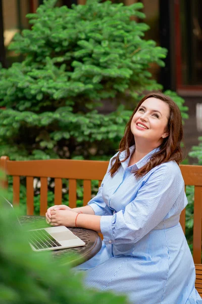 Attraktiv kvinna sitter med laptop i café på gatan, kommunicerar med vän — Stockfoto