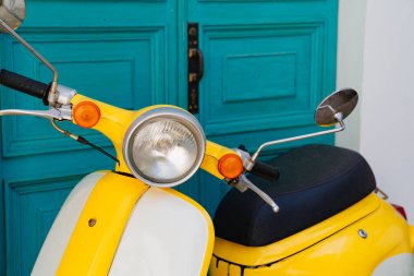 Farlar ve direksiyon. Sarı motosiklet turkuaz ahşap kapıda.