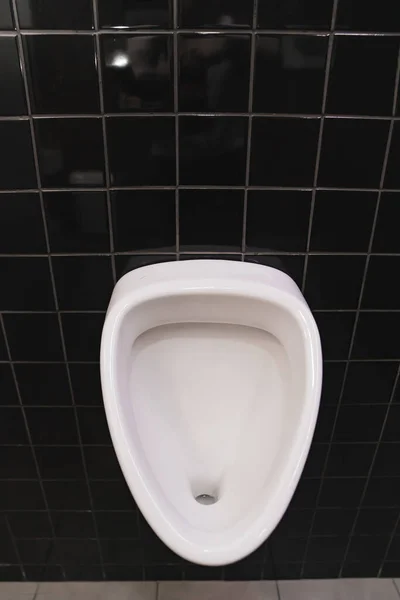 Мужской туалет с писсуаром. туалет комната с черной керамической плиткой на стенах. — стоковое фото