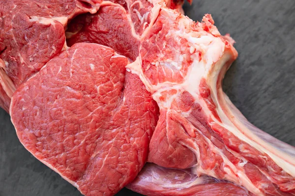 Trozo de carne de res en hueso sobre fondo negro.productos agrícolas naturales y ecológicos —  Fotos de Stock