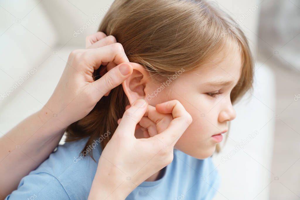 a girl complains of pain in ear and her mother examines it. childrens diseases.