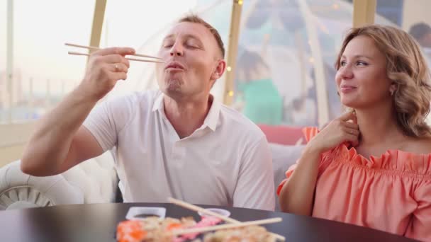 Een man maakt grapjes en voedt een vrouw rolt. romantisch diner en levering van eten. — Stockvideo