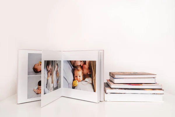 Na mesa branca fotolivro aberto da sessão de fotos da família com recém-nascido. — Fotografia de Stock