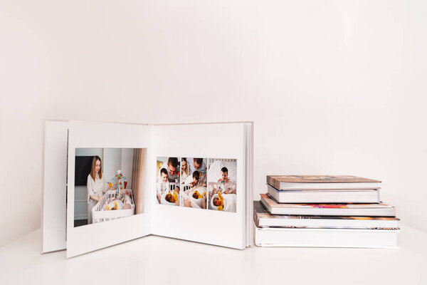 на белом столе открытая фотокнига с фотосессии семьи с новорожденным.