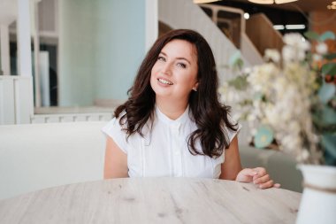 Aydınlık bir odada beyaz elbiseli çekici bir kadın.. 