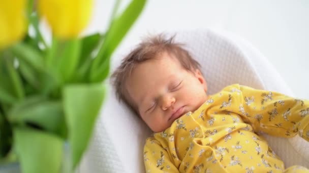 Pasgeboren baby in een geel jumpsuit ligt in een beugel voor de veiligheid van het kind — Stockvideo