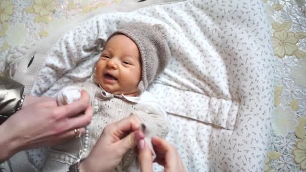 同時に何人かの人が赤ん坊に服を着せる。新生児用の服. — ストック動画