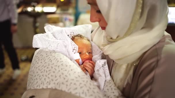 Matka drží a houpe dítě během bohoslužby v kostele. — Stock video