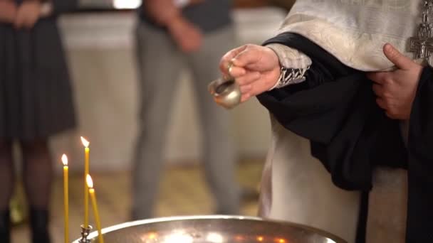 El sacerdote vierte agua bendita en la pila bautismal. — Vídeos de Stock