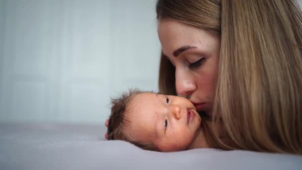 Ibu dengan lembut mencium bayi di tempat tidur. cinta dan kasih sayang seorang ibu. perawatan untuk bayi yang baru lahir — Stok Video