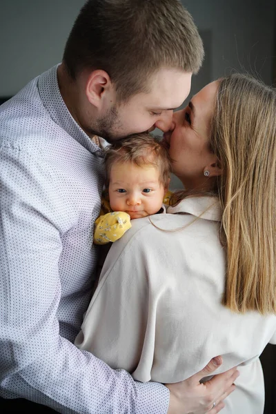 Kärleksfulla föräldrar håller i ett barn och kysser det. faderskapets och moderskapets lycka. — Stockfoto