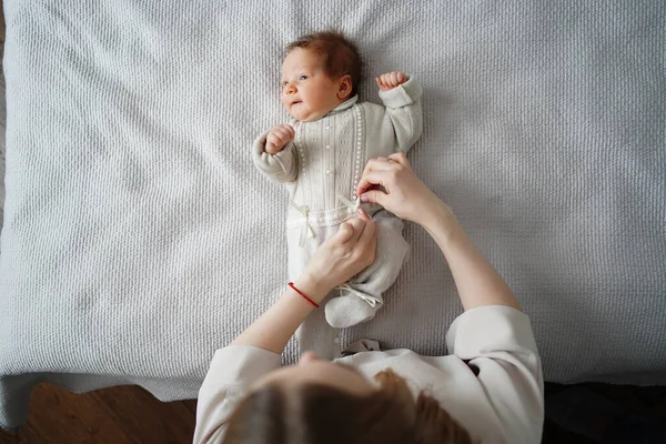 top view. mom changing dress baby on bed in bedroom. clothes for newborns.