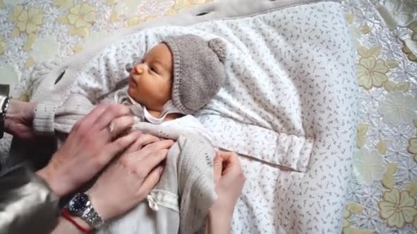 Несколько человек одевают ребенка одновременно. одежда для новорожденных детей. — стоковое видео