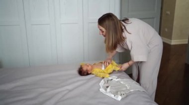 Annem yatak odasında bebeğini değiştiriyor. yeni doğanlar için giysi ve eşyalar.