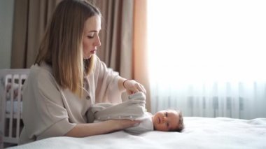 Annem yatak odasında bebeğini değiştiriyor. yeni doğanlar için giysi ve eşyalar.