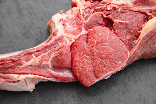 Trozo de carne de res en hueso sobre fondo negro.productos agrícolas naturales y ecológicos —  Fotos de Stock