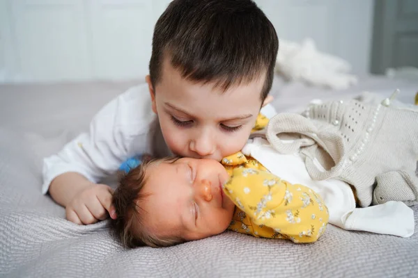Ο μεγαλύτερος αδερφός φιλάει τη νεογέννητη αδερφή. γέννηση του δεύτερου παιδιού στην οικογένεια. — Φωτογραφία Αρχείου