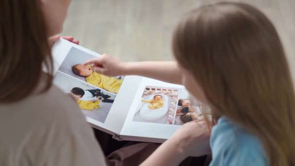 위에서 본 모습. 가족 사진을 찍은 사진이 들어 있는 책을 찾고 있는 어머니와 딸 — 비디오